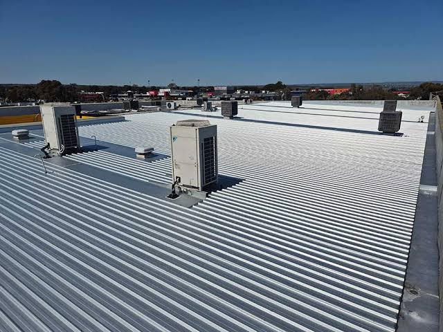 Commercial roof replacement Adelaide - new Colorbond sheeting being laid during a commercial roof replacement on an Adelaide building, Adelaide, Australia
